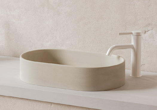 An Eclipse Concrete Basin in the colour Sand on a cream concrete vanity top against a rendered wall.
