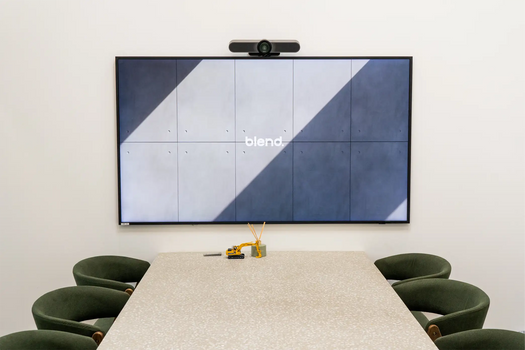 A terrazzo concrete boardroom table in front of a large screen.