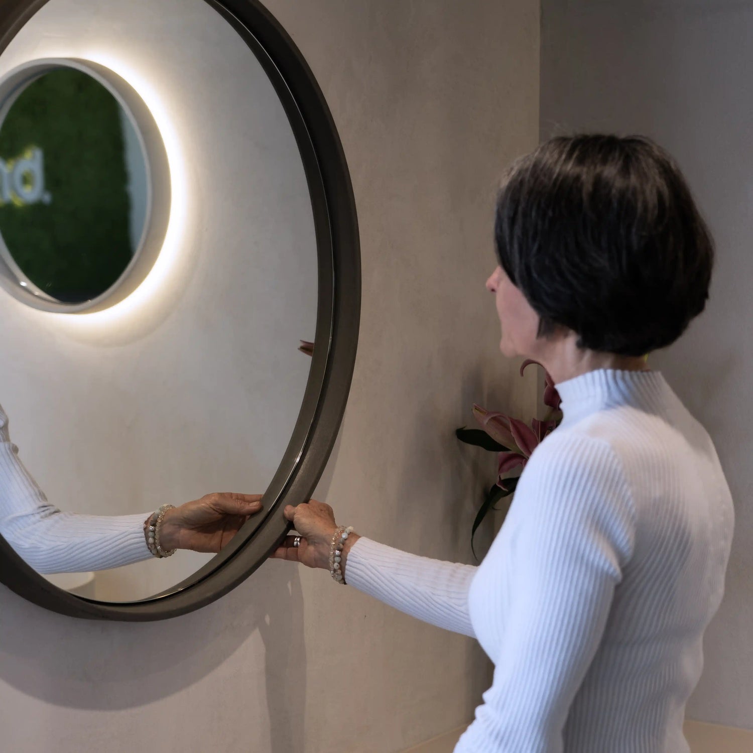 A woman touching the concrete frame of our Sol Concrete Mirror.