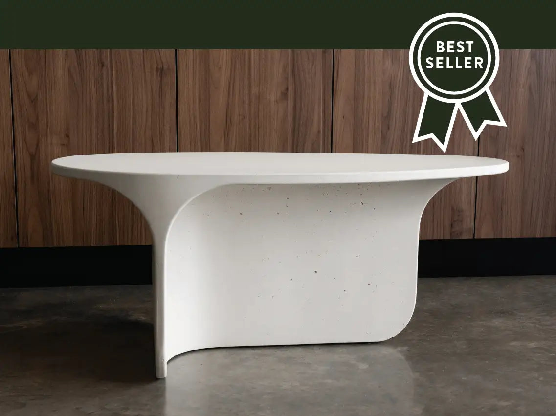 A whitehaven Riviera Concrete Coffee Table in front of walnut cabinetry in a modern living room.