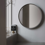 A large Stingray Grey Sol Concrete Mirror on a wall in a modern living room.