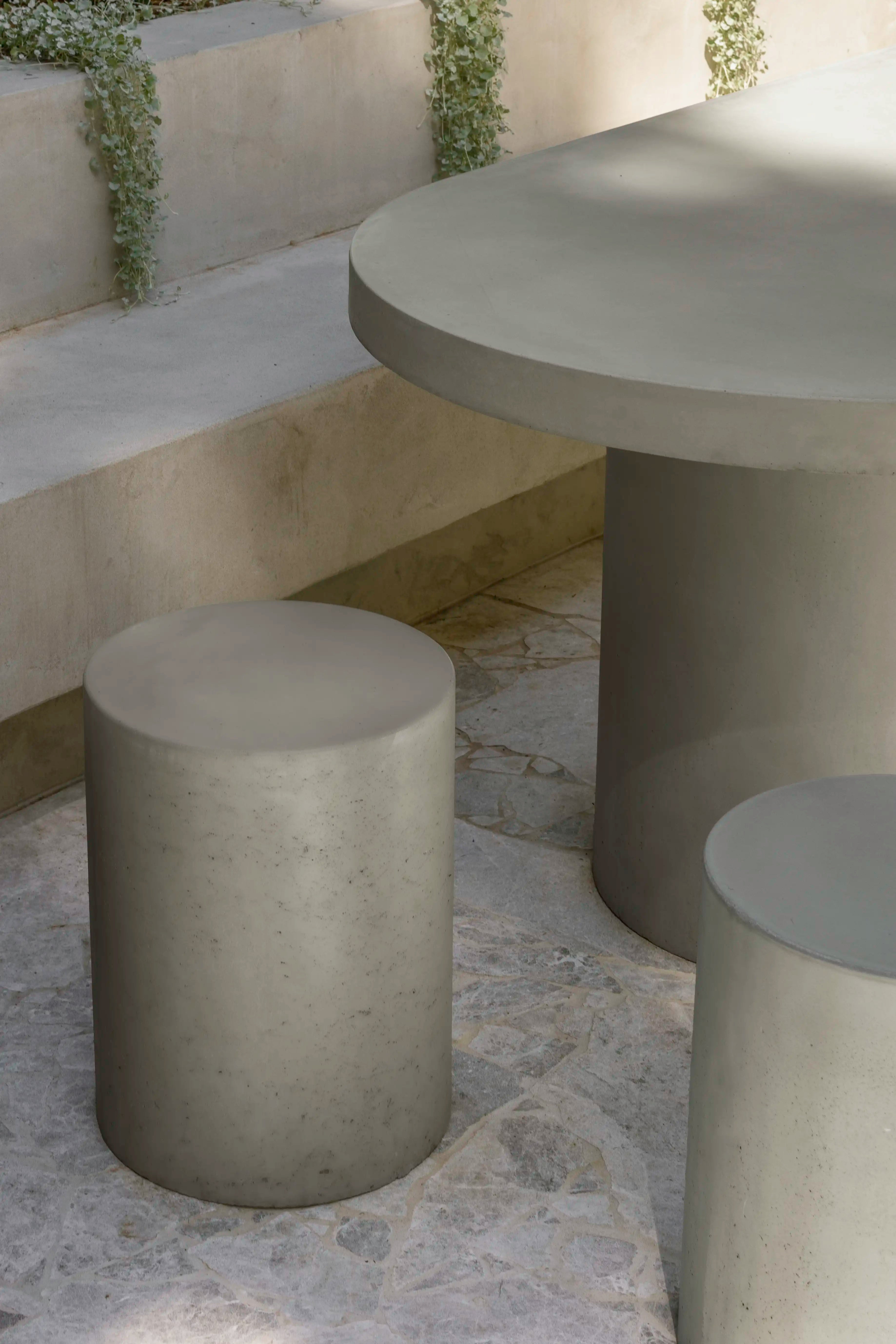 A Dune Concrete Side Table being utilised as a stool n an outdoor area.
