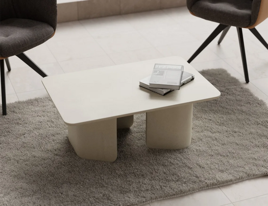 A white Tor Concrete Coffee Table with a shaggy grey rug and two occasion chairs.