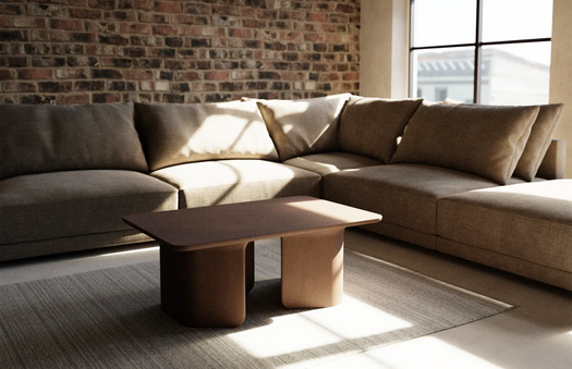 A Dingo Tor Concrete Coffee Table in a loft apartment with brick wall and big windows.
