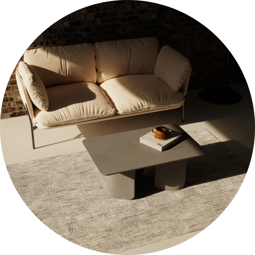 A Granite Grey Concrete Coffee table in front of a white could and on a grey rug.