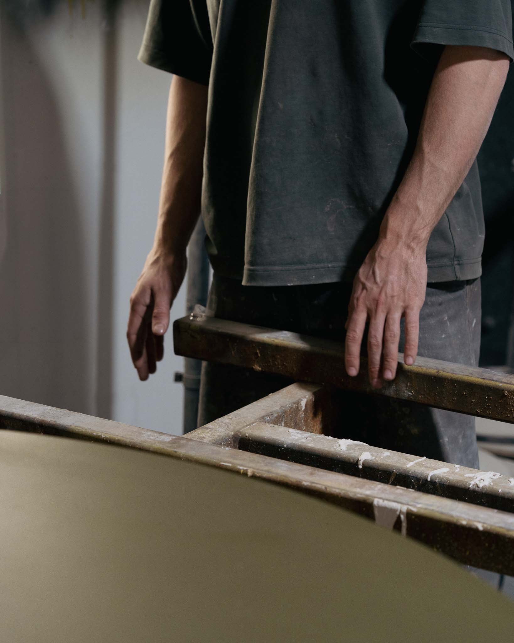 A concrete makers hands near a green concrete dining table.