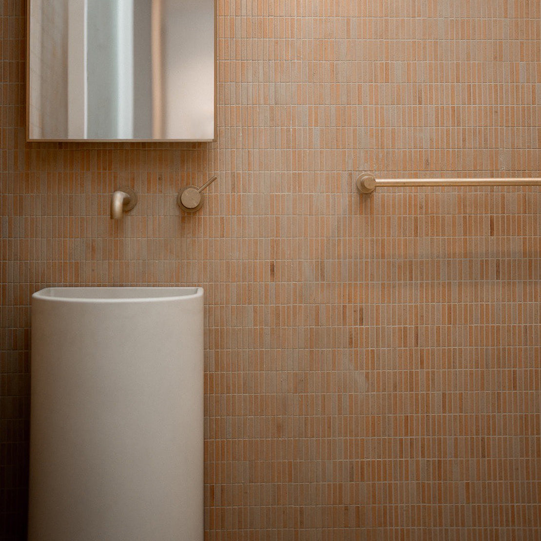 The Aurora Concrete Pedestal Basin in Whitehaven in a peach coloured bathroom with kit kat tiles.