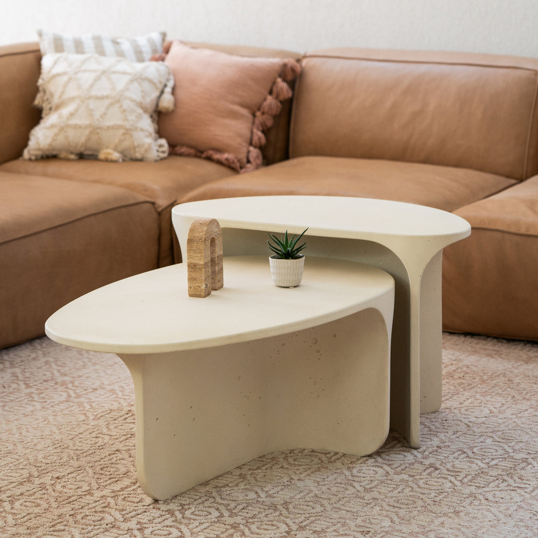 The Riviera Concrete Nesting Set in Sand in front of a brown leather couch.