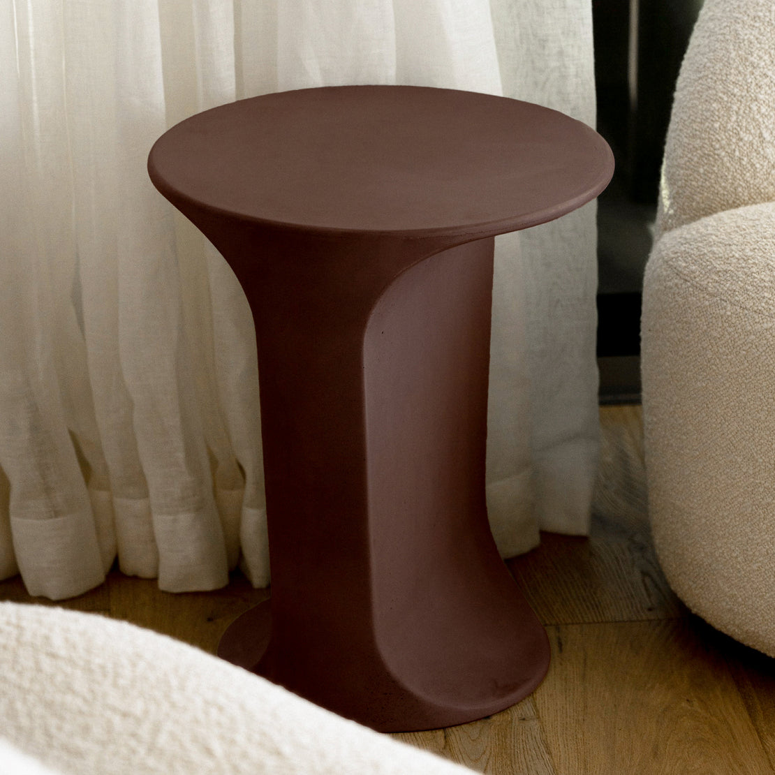 Alpine Concrete Side Table in the rich Merlot colour, featuring a smooth, curved base and round top.