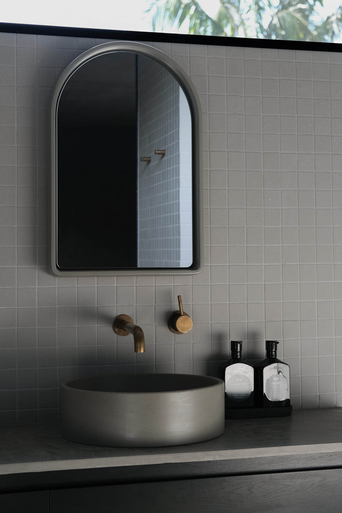 The Arc Concrete Mirror in a grey and black bathroom. The space also features the Comet Concrete Basin.