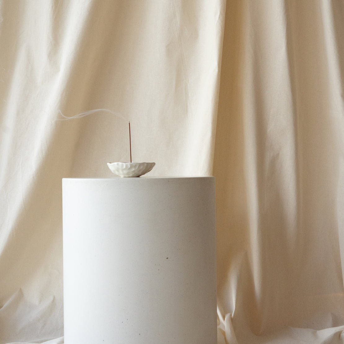 The Dune Concrete Side Table in Whitehaven with incense on top.