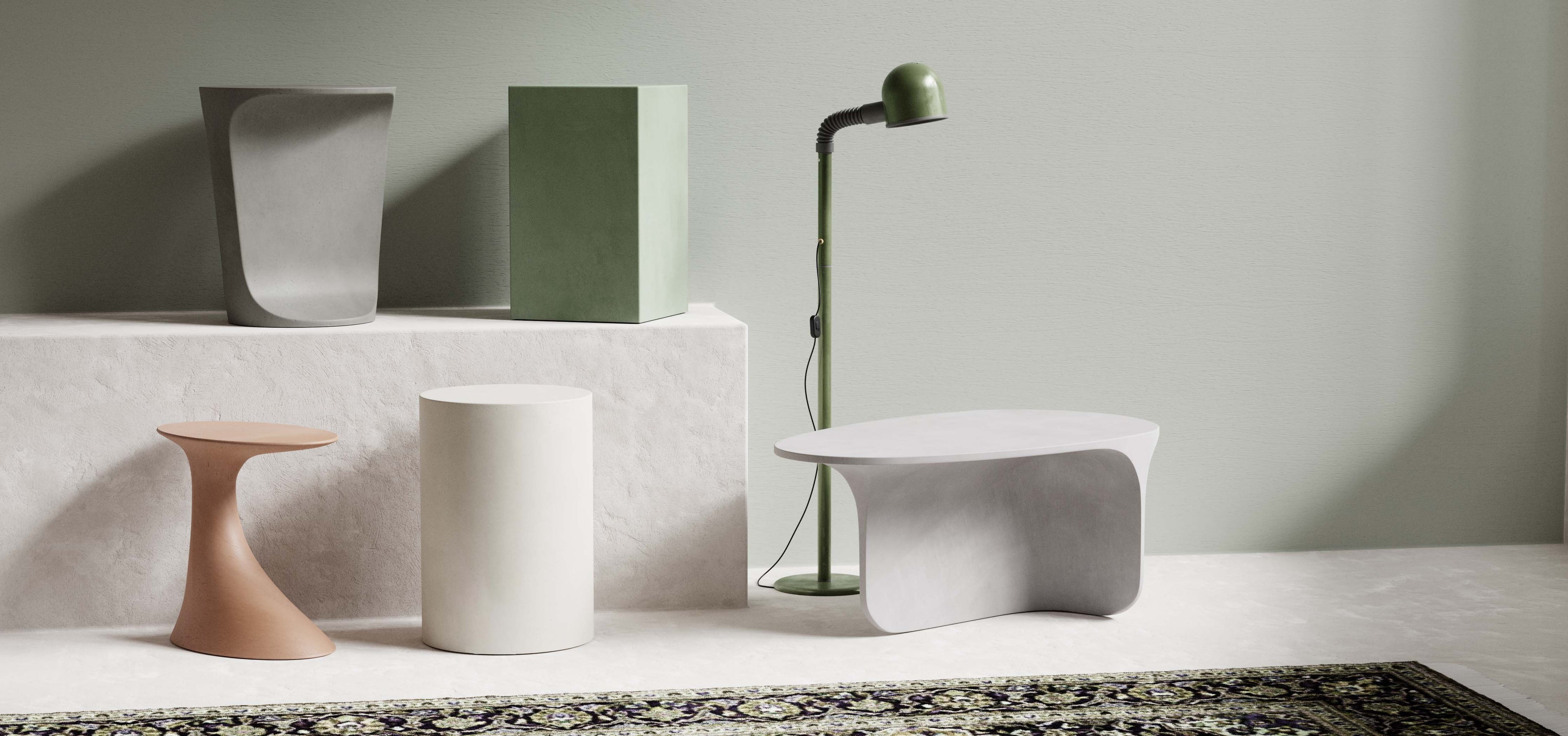 A Oasis Concrete Side Table, Dune Concrete Side Table, Sahara Concrete Side Table, Alpine Concrete Side Table and Riviera Concrete Coffee Table resting on and near a rendered concrete plinth.