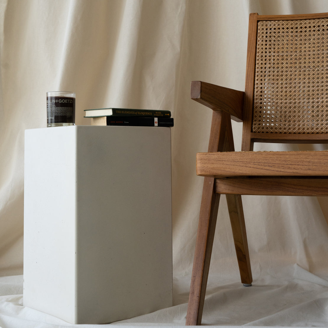 The Sahara Concrete Side Table in Whitehaven styled with books and a candle.