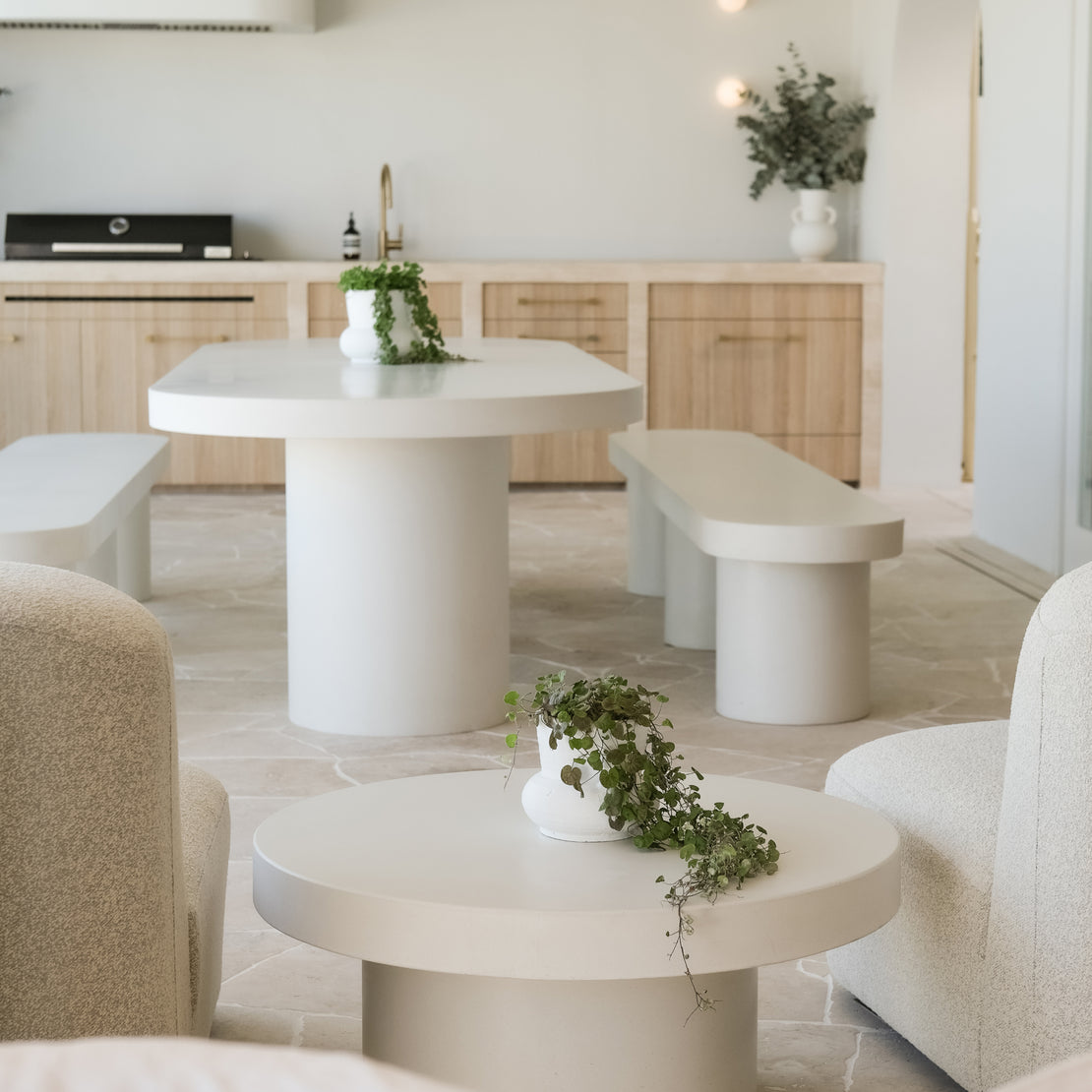 A neutral coloured outdoor area featuring the Siena Concrete Coffee Table and the Umbria Concrete Dining Table with a custom concrete bench.