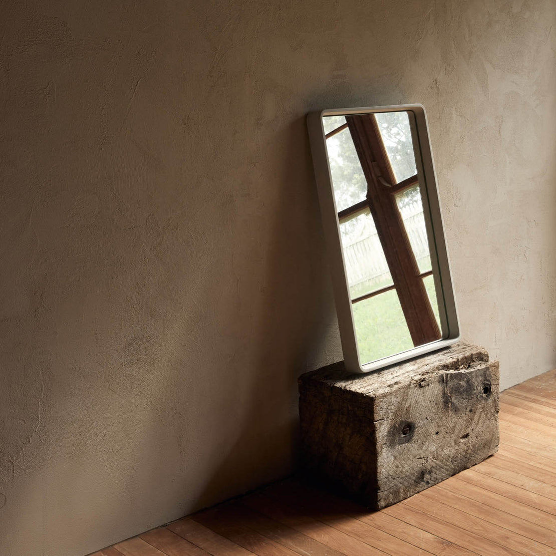 The Stellar Concrete Mirror in Mist. The mirror is leaning against a wall in a neutral toned room.