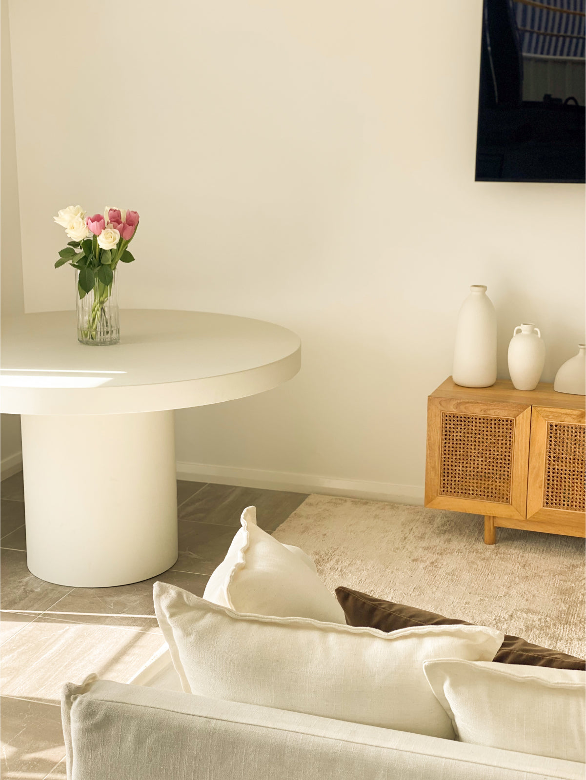 A Small Tuscan Concrete Dining Table in Whitehaven in a living room with a vase filled with roses