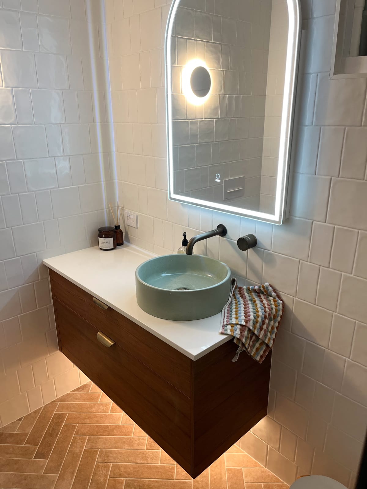 Comet Concrete Basin in Rainforest  Green on a wooden vanity, and white tiling behind