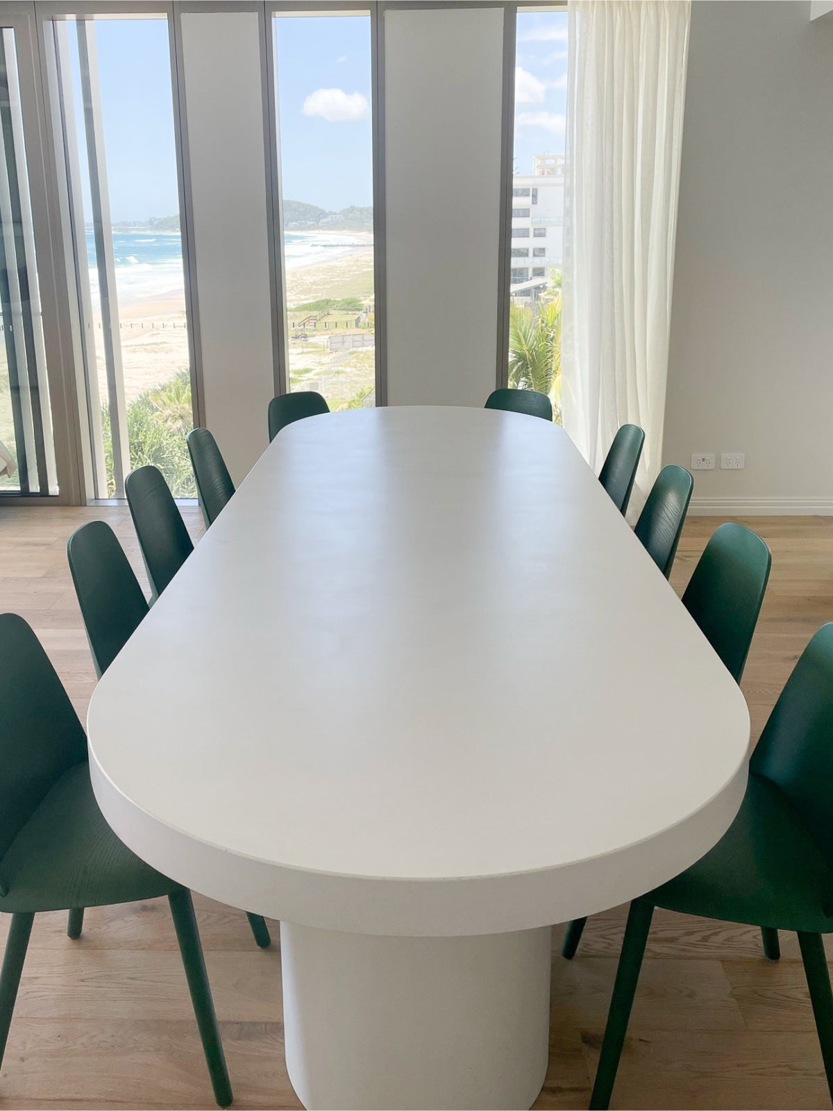 The Umbria Concrete Dining Table with green chairs surrounding