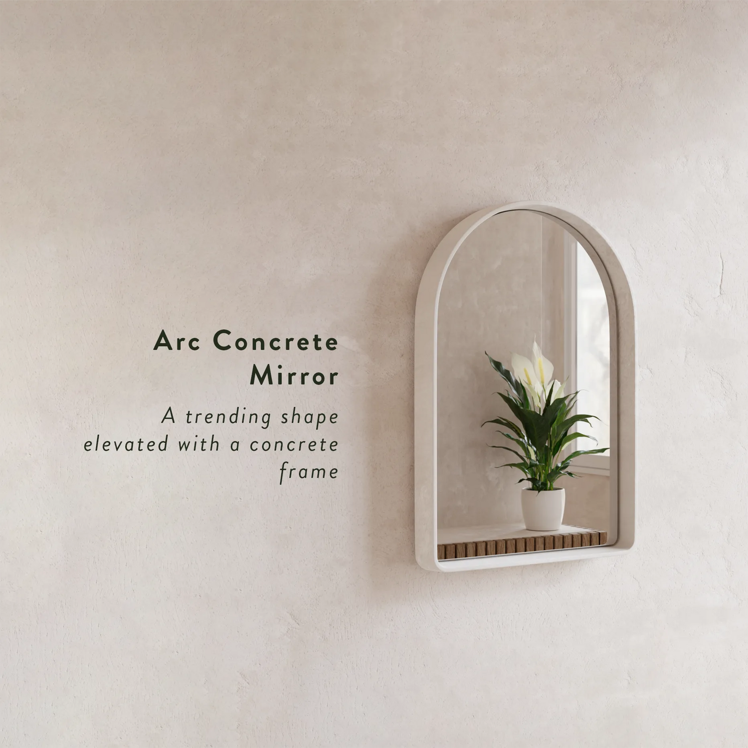 A white Arc Concrete Mirror mounted on a cream microcement rendered wall with the text "Arc Concrete MIrror - a trending shape elevated with a concrete frame"