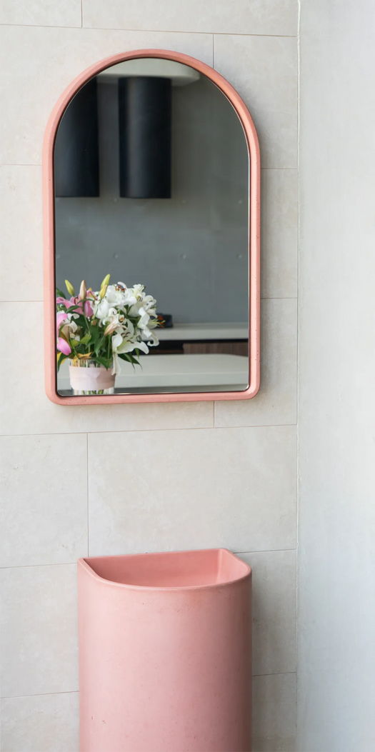 A matching pink Aurora Concrete Basin which is a freestanding basin and a matching pink Arc Concrete Mirror in the Blend Concrete Design showroom.