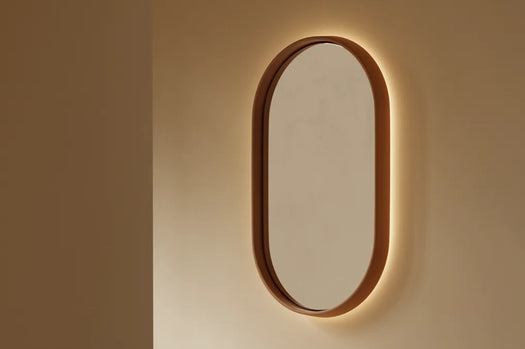 A Dingo Lunar Concrete LED Mirror on a beige wall in a modern living room.