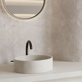 A close up of the round Comet Concrete Basin in the colour whitehaven in a minimalist rendered bathroom. 