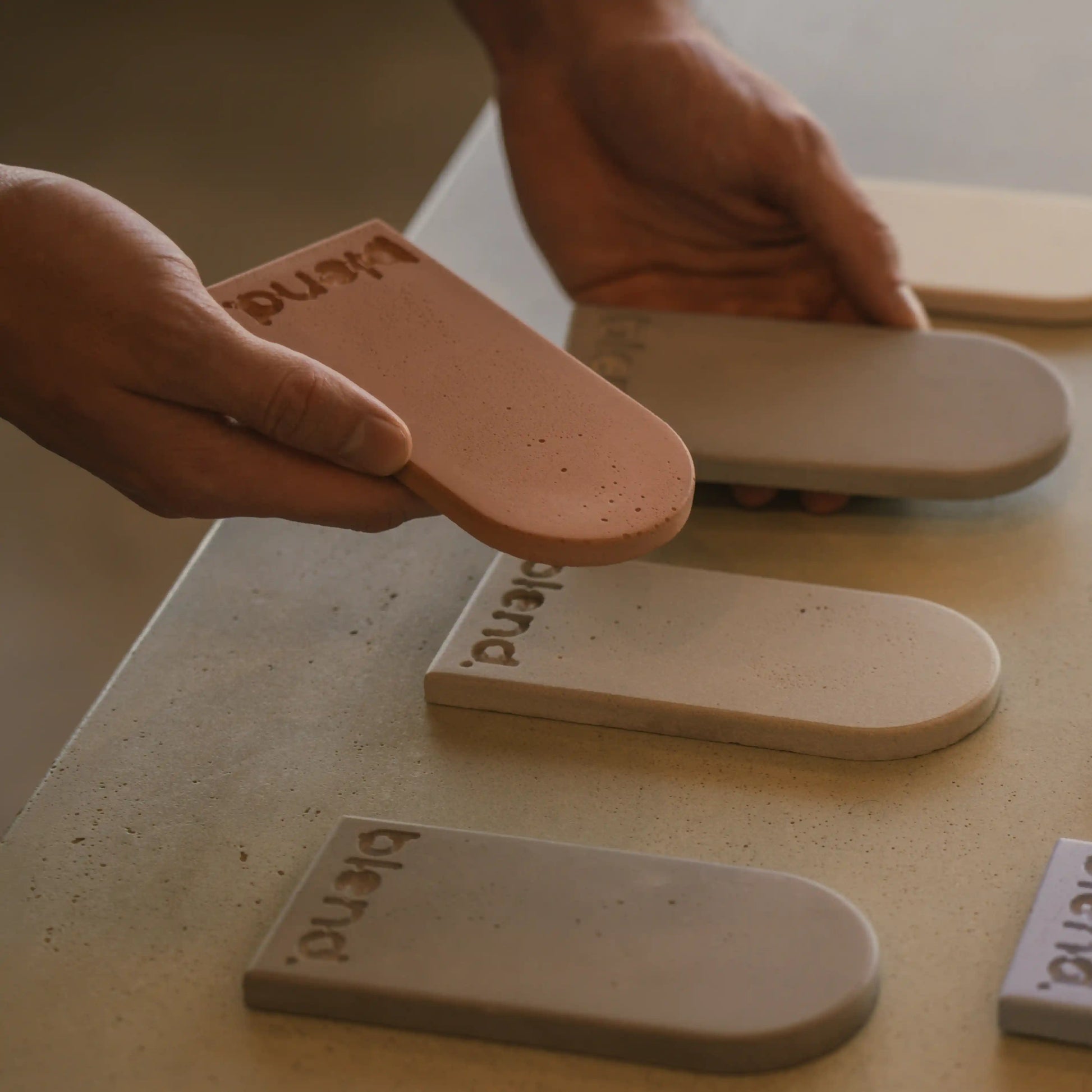 A close up of a hand holding two Blend Concrete Design concrete colour samples.