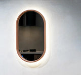 A Dingo Lunar Concrete LED Mirror on a white rendered wall in a living room.
