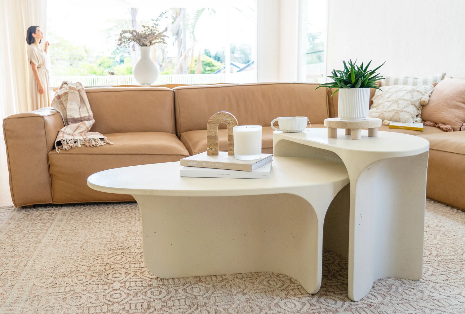 The Riviera Concrete Coffee Table and Adria Concrete Side Table in front of a tan couch in a bright modern living room.