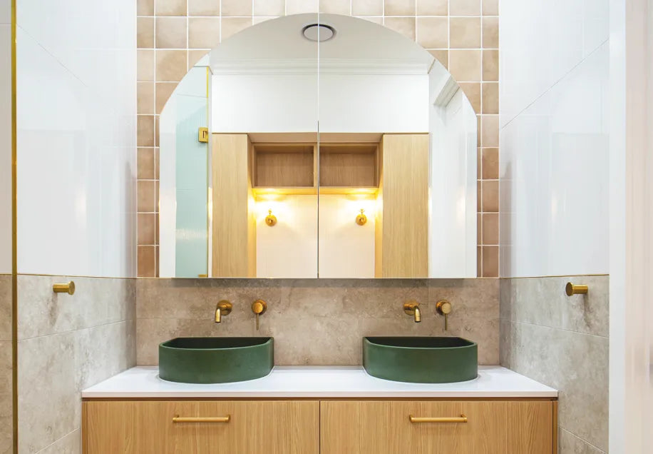 Two Crescent Concrete Basins in a custom green colour in a bathroom using neutral tones and brass fittings.