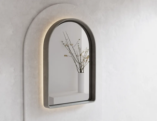 A Koala Grey Arc Concrete LED mirror on a white rendered wall in a modern living room.