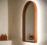 The side of a terracotta coloured Arc Concrete Mirror in a modern bathroom and the LED backlighting turned on.