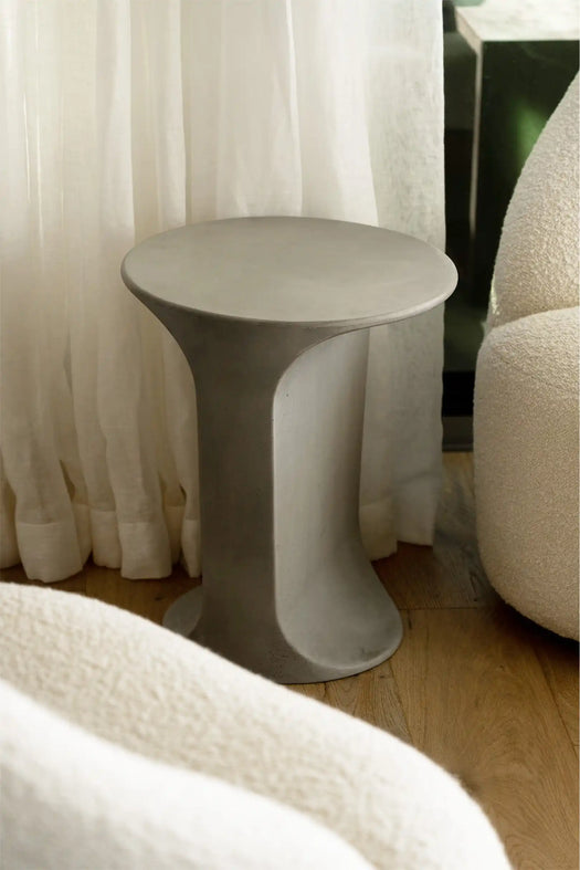 A Mist Grey Alpine Concrete Side Table next to a fluffy living room chair.