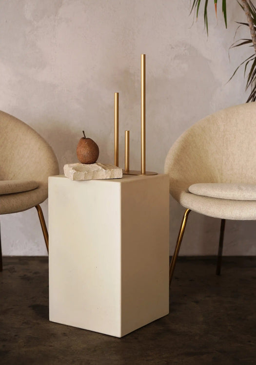 A Sand Coloured Sahara Concrete Side Table in between two stylish cream chairs in a modern living room.