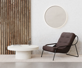 A white round concrete coffee table with a leather occasional chair and a round concrete LED mirror.
