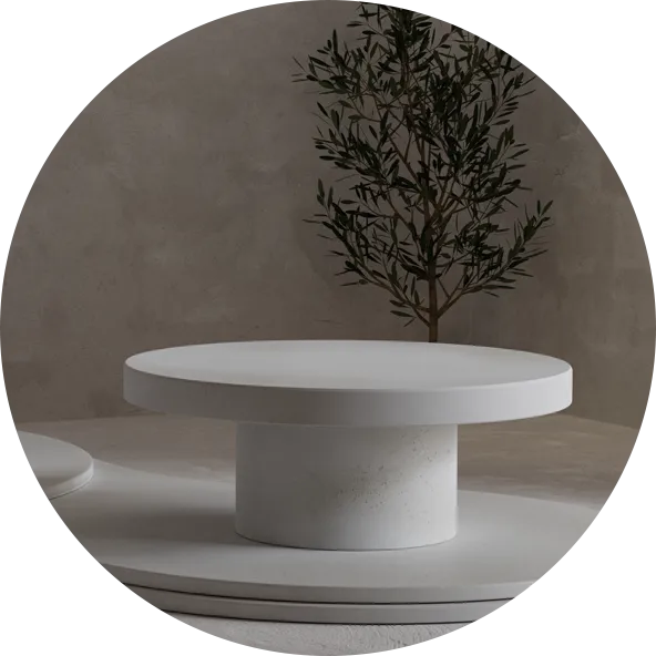 A round Concrete Coffee Table in front of a microcement rendered wall and with an olive tree.
