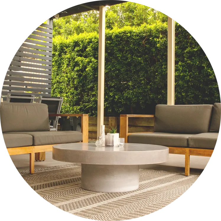 A Koala Grey round concrete Coffee Table in a outdoor living areas with two outdoor sofas on a rug.