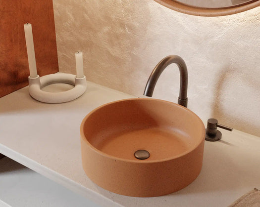 A Comet Concrete Basin installed in a contemporary and bright bathroom with an orange feature wall.