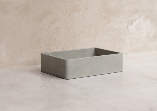 A Stingray Grey Nova Concrete Basin on a white concrete floor in front of a micro cement rendered wall. 