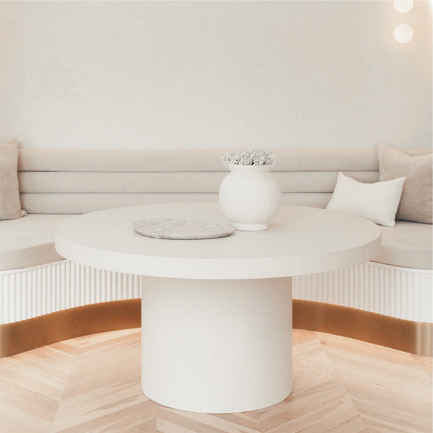 A Tuscan Concrete Dining Table sitting in front of a curved couch booth. 