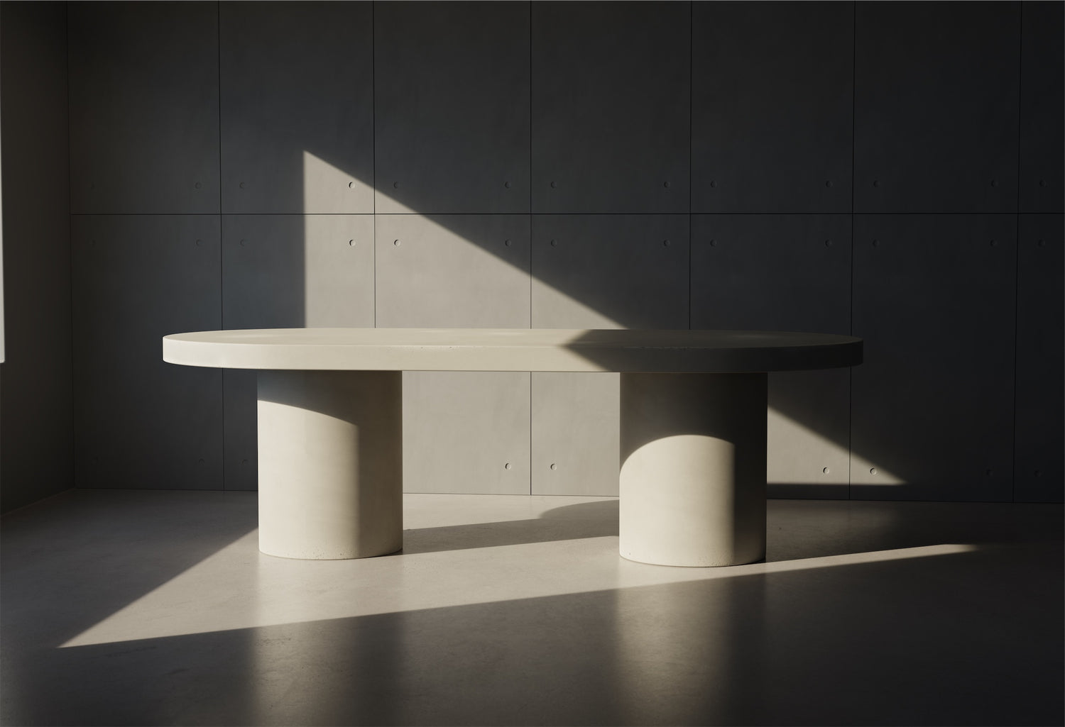 A Verona Concrete Dining Table sitting in front of a Concrete Panel wall 